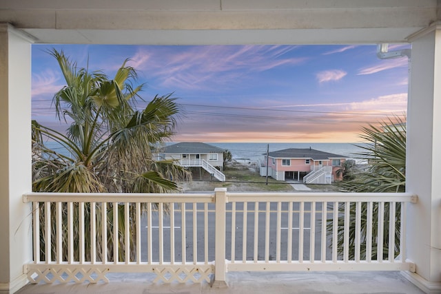 balcony at dusk featuring a water view