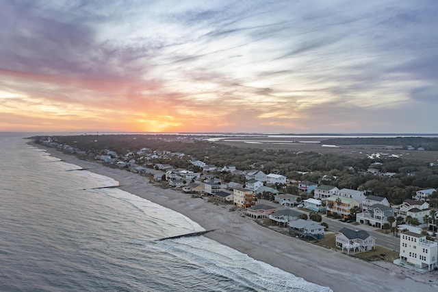 aerial view at dusk featuring a view of the beach and a water view