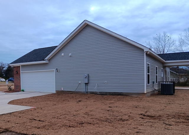 view of property exterior with a garage, driveway, roof with shingles, and central air condition unit