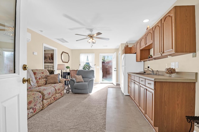 kitchen featuring light carpet, sink, ceiling fan, and white refrigerator