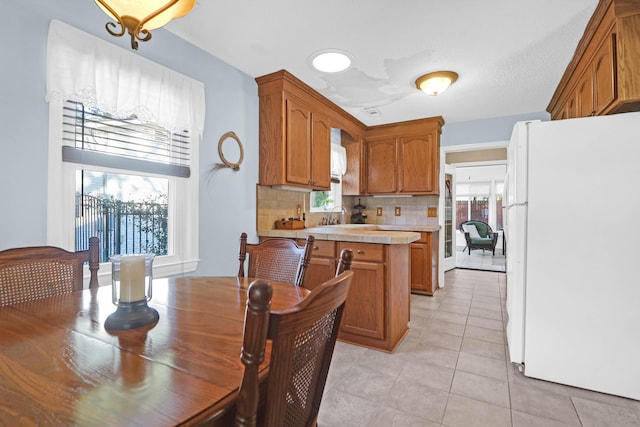 kitchen featuring backsplash, sink, light tile patterned floors, and white refrigerator