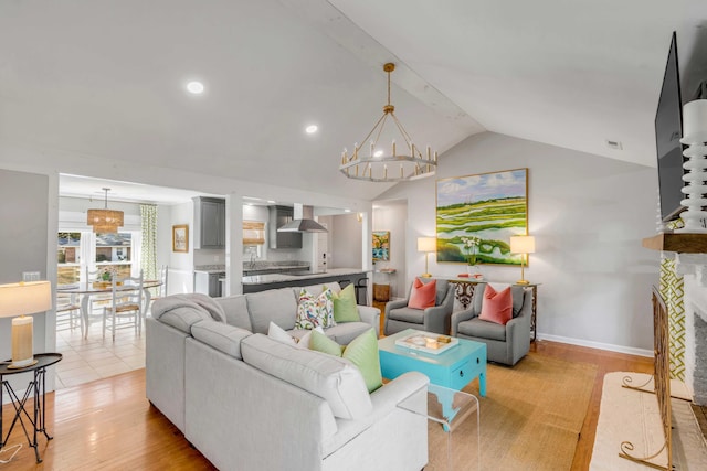 living room featuring recessed lighting, a fireplace with flush hearth, baseboards, vaulted ceiling, and light wood finished floors