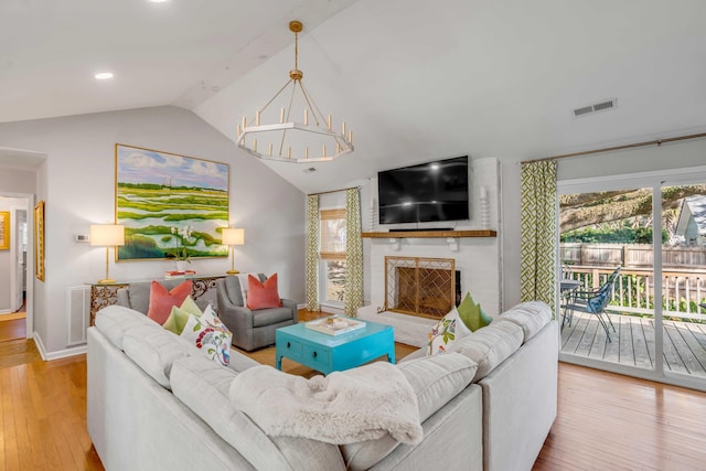 living room featuring lofted ceiling, hardwood / wood-style flooring, a fireplace, and visible vents