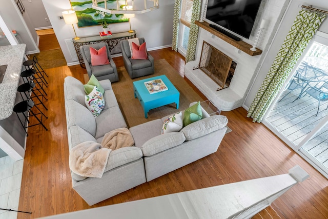 living room with a fireplace with raised hearth, wood finished floors, and baseboards