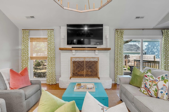 living area with visible vents, a fireplace, and wood finished floors