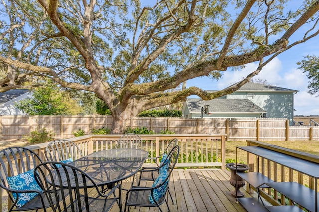 wooden deck with a fenced backyard and outdoor dining space