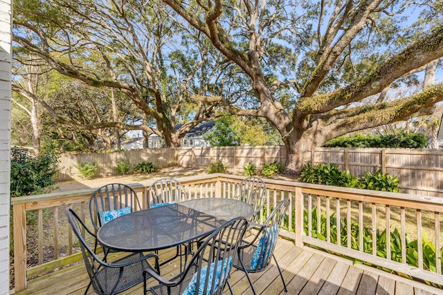 wooden terrace with outdoor dining space and a fenced backyard