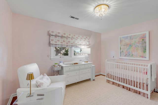 bedroom featuring a crib, light colored carpet, visible vents, and baseboards