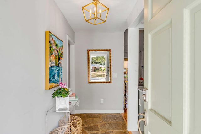 foyer entrance featuring a notable chandelier and baseboards