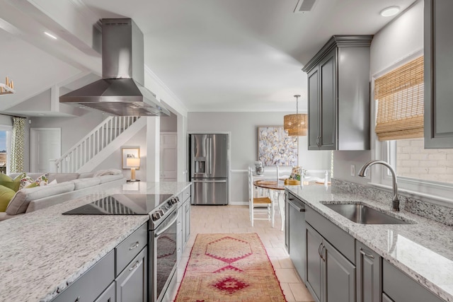 kitchen with wall chimney range hood, stainless steel appliances, a sink, and gray cabinetry