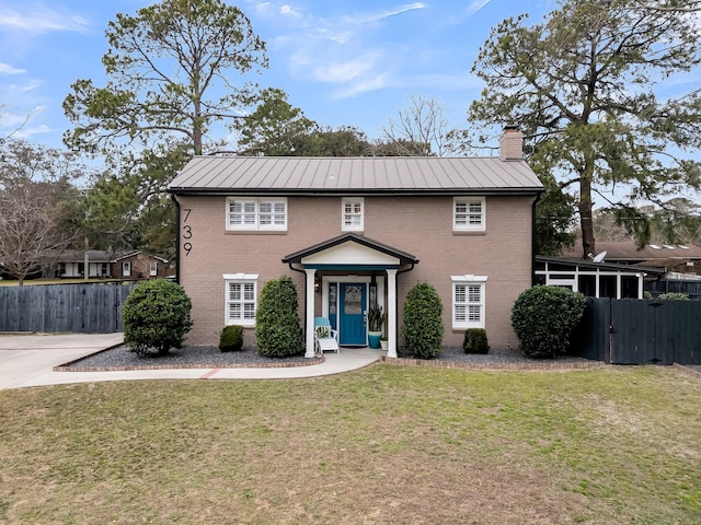 colonial inspired home with brick siding, a standing seam roof, and fence