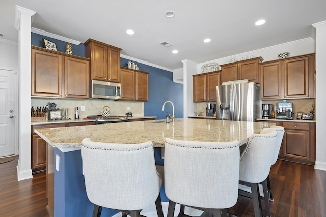 kitchen with dark wood-style floors, a large island, visible vents, appliances with stainless steel finishes, and a sink