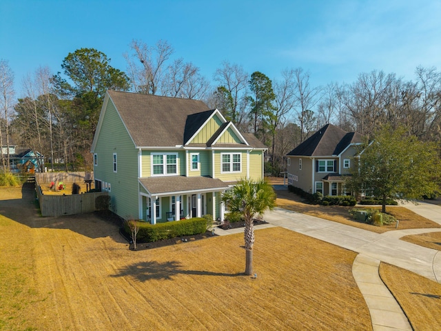 craftsman house featuring board and batten siding, a front yard, concrete driveway, and fence