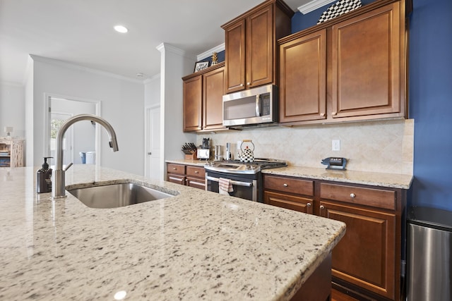 kitchen featuring light stone counters, a sink, stainless steel appliances, crown molding, and backsplash