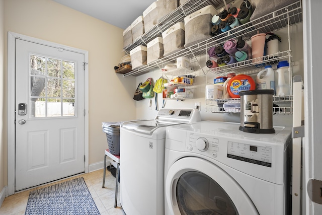 washroom with laundry area, light tile patterned flooring, baseboards, and washing machine and clothes dryer