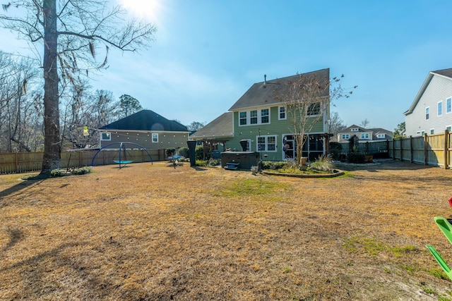 back of house with a lawn, a fenced backyard, and a hot tub