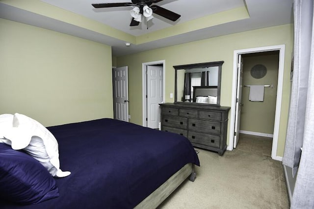 bedroom featuring a raised ceiling, light colored carpet, and ceiling fan