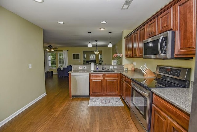 kitchen with pendant lighting, sink, appliances with stainless steel finishes, dark hardwood / wood-style floors, and kitchen peninsula