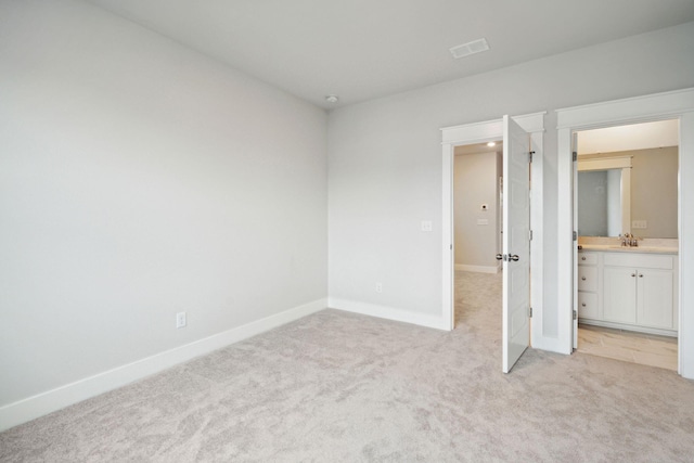 unfurnished bedroom with sink, ensuite bathroom, and light carpet