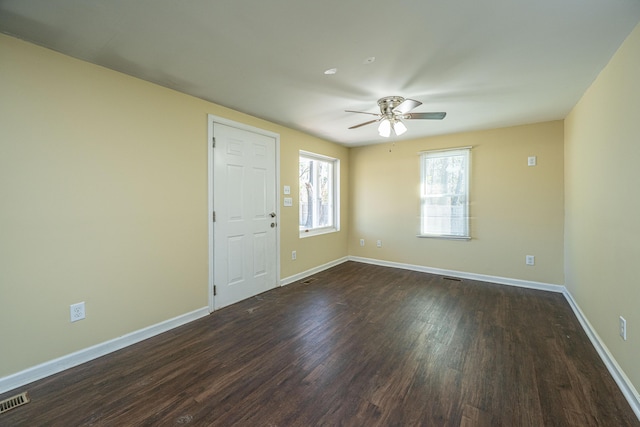 empty room featuring a ceiling fan, visible vents, baseboards, and dark wood-type flooring