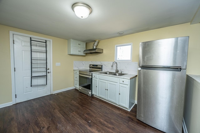 kitchen featuring light countertops, appliances with stainless steel finishes, white cabinets, a sink, and wall chimney exhaust hood