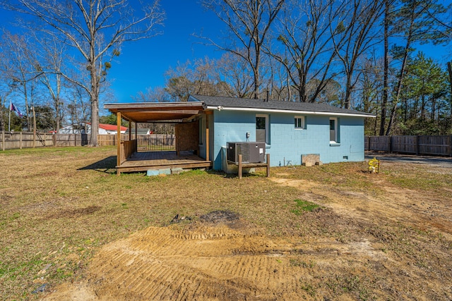 back of house with a fenced backyard, concrete block siding, central AC, and a yard