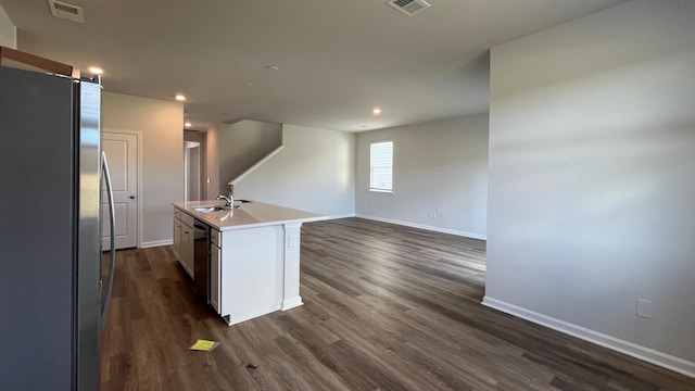 kitchen featuring an island with sink, sink, dark wood-type flooring, and stainless steel refrigerator