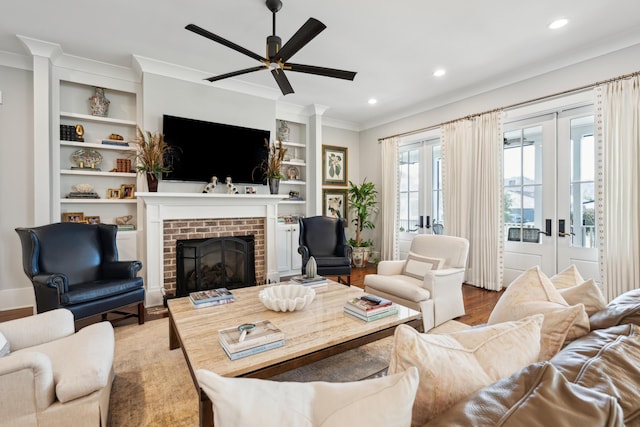 living area with built in features, a brick fireplace, french doors, and ornamental molding