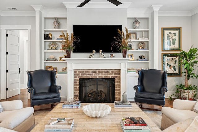 living area featuring built in features, visible vents, crown molding, and wood finished floors