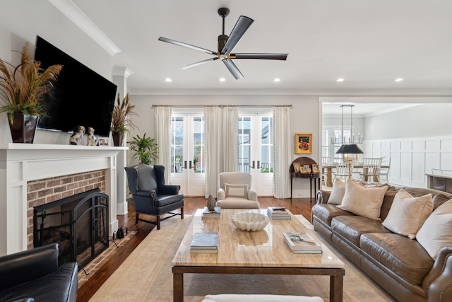 living area featuring ornamental molding, a brick fireplace, a healthy amount of sunlight, and wood finished floors