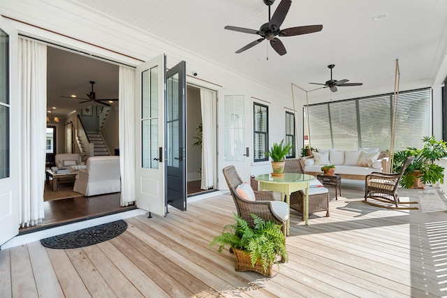 wooden deck with ceiling fan and outdoor lounge area