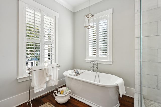 full bath featuring baseboards, ornamental molding, a freestanding bath, and wood finished floors