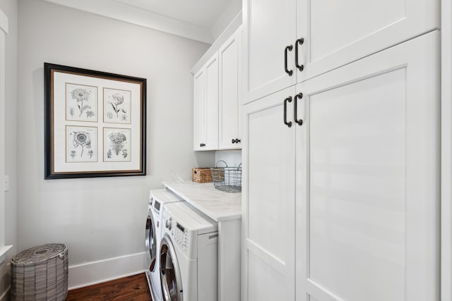 laundry room with dark wood-style flooring, washing machine and dryer, cabinet space, and baseboards