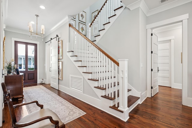 foyer with baseboards, a barn door, ornamental molding, and dark wood-style flooring