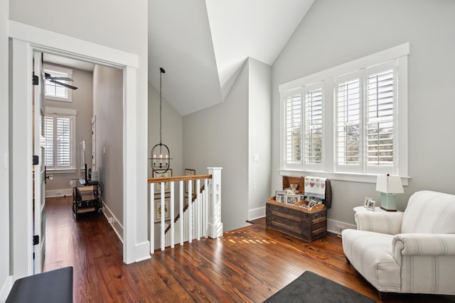 living area with a notable chandelier, dark wood-type flooring, an upstairs landing, baseboards, and vaulted ceiling