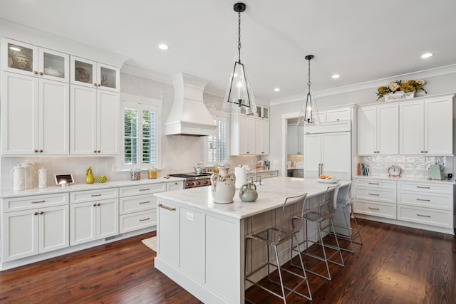 kitchen with white cabinets, custom range hood, glass insert cabinets, a center island, and light stone countertops