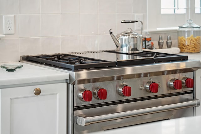 interior details with light countertops, high end range, and white cabinetry