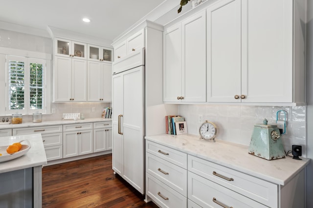 kitchen featuring light stone counters, backsplash, glass insert cabinets, white cabinets, and paneled refrigerator