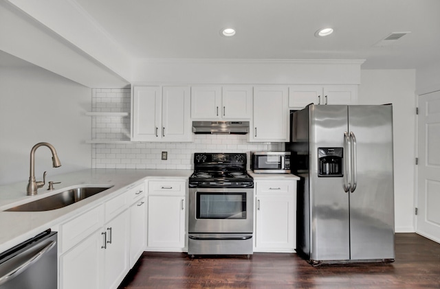 kitchen with sink, backsplash, white cabinets, and appliances with stainless steel finishes