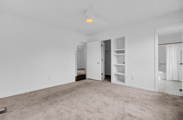 unfurnished bedroom with ensuite bath, carpet floors, ceiling fan, and a spacious closet