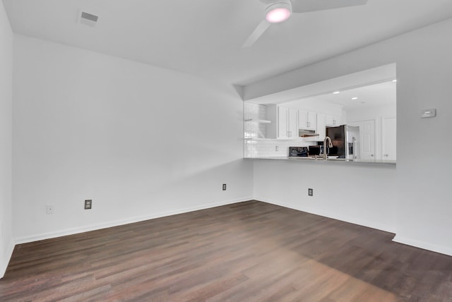 unfurnished living room with ceiling fan, sink, and dark hardwood / wood-style flooring