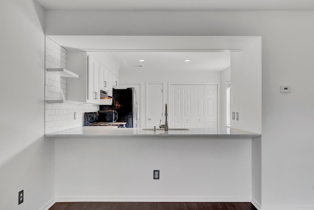 kitchen with white cabinetry, sink, stainless steel fridge, decorative backsplash, and kitchen peninsula