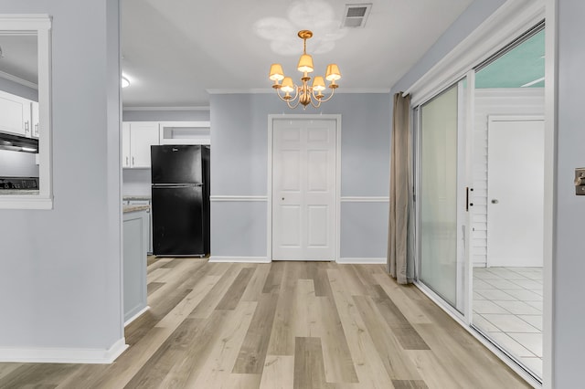 kitchen with white cabinetry, black fridge, light hardwood / wood-style flooring, a notable chandelier, and decorative light fixtures