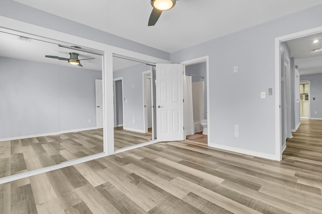 unfurnished bedroom featuring ceiling fan, ensuite bathroom, and light hardwood / wood-style floors