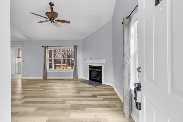 unfurnished living room with ceiling fan, light wood-type flooring, and lofted ceiling