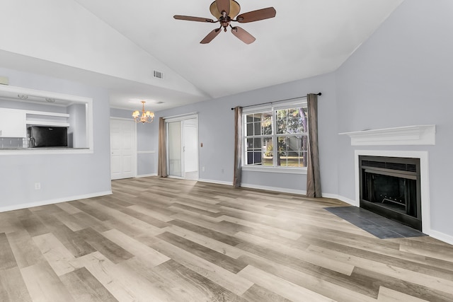 unfurnished living room featuring ceiling fan with notable chandelier, light wood-type flooring, and high vaulted ceiling