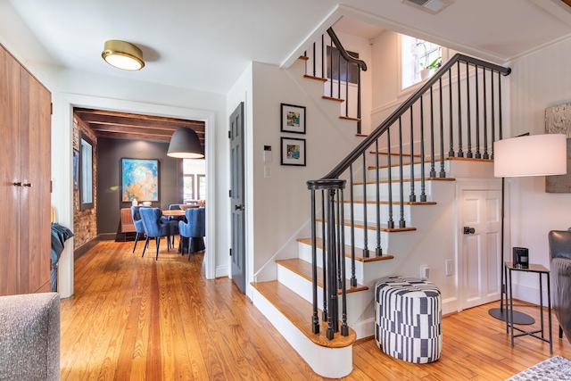 stairs featuring healthy amount of natural light, wood-type flooring, and baseboards
