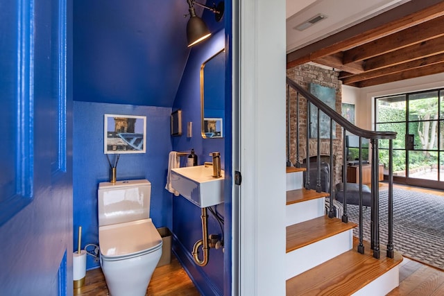 half bath featuring a sink, toilet, and wood finished floors