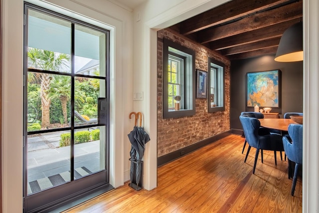 doorway to outside featuring wood finished floors, baseboards, and beamed ceiling