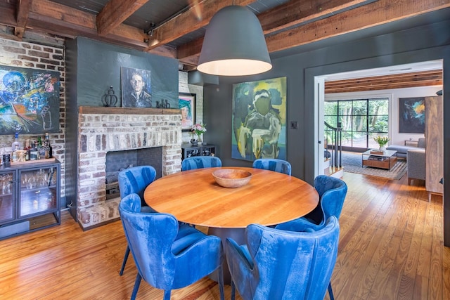dining area with beamed ceiling, wood-type flooring, a fireplace, and wooden ceiling